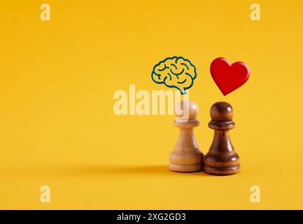 Logique versus émotion concept. Pensée rationnelle ou émotionnelle ou prise de décision. Pions d'échecs avec des symboles de cerveau humain et de coeur sur fond jaune. Banque D'Images