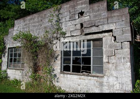 Bâtiment abandonné en blocs de béton avec mur en ruine et verre brisé Banque D'Images