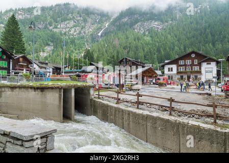 Débordement d'un torrent, inondations et glissements de terrain parmi les maisons d'un village de montagne. Centre de Macugnaga, Italie, avec sauvetages et pompiers Banque D'Images