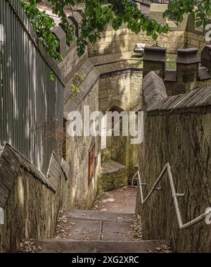 Section intérieure d'un mur historique de la ville. Des marches mènent vers le bas à une ouverture dans le mur et les rampes sont d'un côté. Les feuilles d'un arbre sont au-dessus et a Banque D'Images