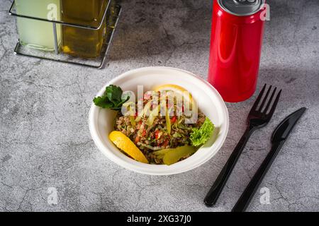 Salade de quinoa sur une assiette blanche en styromousse sur une table en pierre Banque D'Images