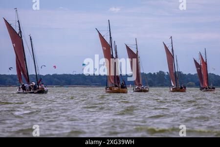 Wustrow, Allemagne. 06 juillet 2024. Zeesboats, jusqu'à 12 mètres de long, des bateaux à épée stables de l'époque de la pêche à la voile avec les voiles brunes typiques, naviguent à la 38e Wustrower Zeesbootregatta sur le Saaler Bodden entre le continent et la péninsule de Fischland-Darss-Zingt. La régate se déroule en trois classes de bateaux dans des vents forts et des vagues. Crédit : Jens Büttner/dpa/Alamy Live News Banque D'Images