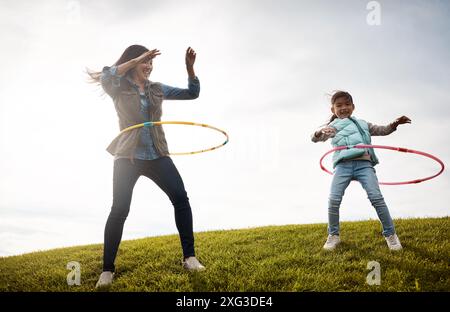 Mère, enfant et danse avec cerceau dans le champ, jeu et nature en automne pour l'activité. Fille, ensemble et liaison avec une personne féminine ou maman avec une fille Banque D'Images