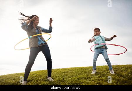 Cerceau, jouer et danser pour maman avec fille, jouets et plaisir dans la nature pour l'activité de vacances. Fille, anneau en plastique et collage pour femme personne avec enfant Banque D'Images