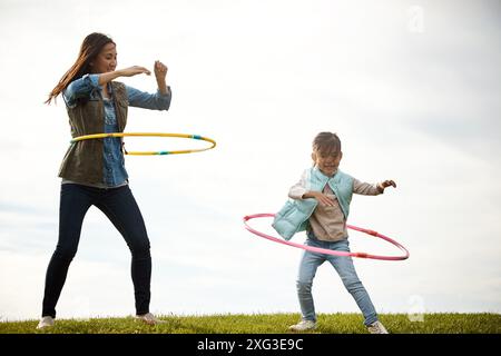 Mère, fille et plaisir avec cerceau dans le champ, jouets et nature en automne pour l'activité. Fille, ensemble et liaison avec une personne féminine ou maman avec enfant Banque D'Images