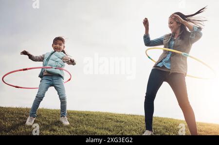 Mère, enfant et danse avec cerceau dans le champ, jeu et nature en automne pour l'activité. Fille, ensemble et liaison avec une personne féminine ou maman avec une fille Banque D'Images