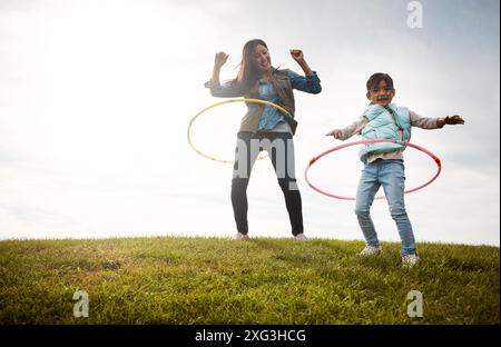 Fille, femme et cerceau dans le champ avec plaisir et jouet, baby-sitter et énergie dans la nature pour l'activité de vacances. Garde d'enfants, amour et bague en plastique avec femelle Banque D'Images