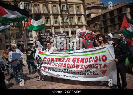 Malaga, Espagne. 06 juillet 2024. On voit des manifestants tenir une banderole, des pancartes et des drapeaux palestiniens alors qu'ils participent à une manifestation de solidarité avec le peuple palestinien. Sous le slogan "contre le génocide et l'occupation sioniste", des dizaines de personnes exigent la fin du commerce des armes et des relations commerciales avec Israël, dans le contexte des conflits en cours entre Israël et le Hamas. Crédit : SOPA images Limited/Alamy Live News Banque D'Images