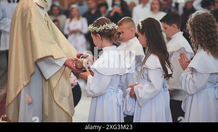 Lida, Biélorussie - 31 mai 2022 : les enfants reçoivent du pain du prêtre de l'Église catholique. Banque D'Images