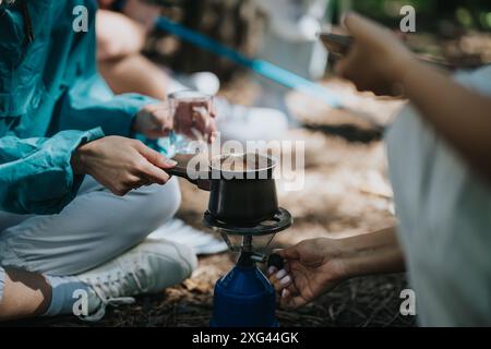 Amis préparant le café sur un poêle de camping portable dans une forêt Banque D'Images