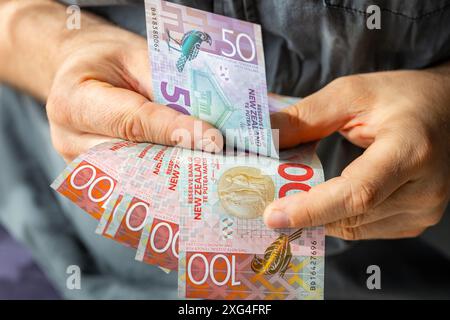 Argent néo-zélandais, homme comptant les dollars néo-zélandais, gros plan des mains avec des billets de banque Banque D'Images