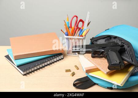 Arme à feu, balles et papeterie scolaire sur table en bois Banque D'Images