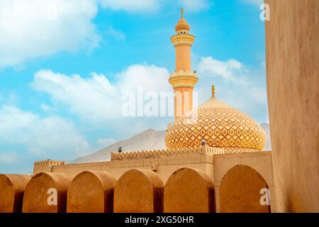 Mosquée Al Qala'a orné dôme et minaret avec murs du château de Nizwa au premier plan, Nizwa, sultanat Oman Banque D'Images