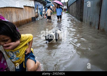 Les Népalais marchent le long d'une rue inondée alors qu'une rivière déborde après de fortes pluies dans la région de Teku. Après de fortes pluies à travers le pays, de nombreuses régions ont été coupées car les inondations et les glissements de terrain ont balayé des ponts et des tronçons de routes sur certaines autoroutes. Banque D'Images