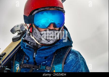 Gros plan portrait de lunettes de ski d'un homme avec reflet de montagnes enneigées. La chaîne de montagnes se reflète dans le masque de ski. Portrait d'un homme dans un Banque D'Images