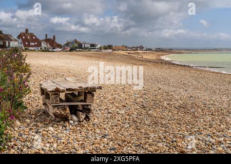 La plage de galets de Pevensey Bay, East Sussex, Angleterre, avec deux palettes clouées l'une sur l'autre pour servir de banc Banque D'Images