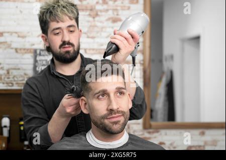 Coiffeur séchage des cheveux du client. Photo de haute qualité Banque D'Images