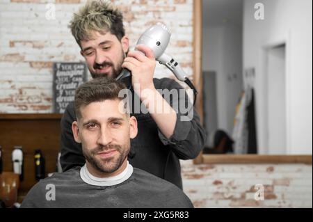 Coiffeur séchage des cheveux du client. Photo de haute qualité Banque D'Images