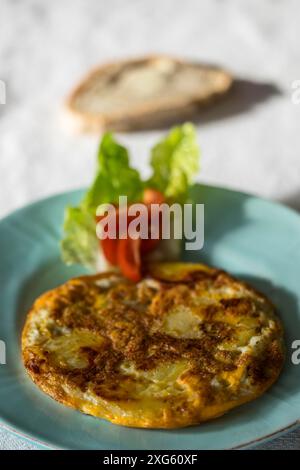 Tortilla espanola sur une assiette avec tomate Banque D'Images