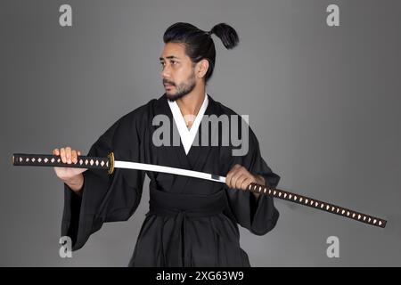 Modèle homme Asain en robe de tradition japonaise kimono avec épée de samouraï sur fond isolé Banque D'Images