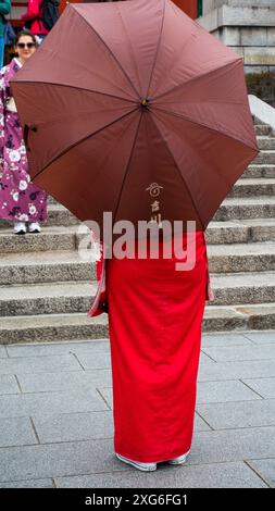 JAPON, KYOTO – avril 2024 : jeune fille vêtue de kimono tenant un parapluie au temple du sanctuaire Fushimiinari Taisha à Kyoto, au Japon Banque D'Images