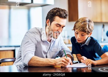 Papa, aidant et fils avec les devoirs, la maison et l'écriture dans la cuisine, le calcul et les mathématiques le matin sur la table. Maison, apprentissage et éducation pour enfant Banque D'Images