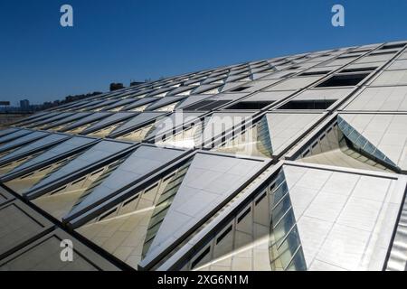 Détail architectural moderne d'une structure de toit géométrique en verre et en métal reflétant la lumière du soleil sous un ciel bleu clair à la bibliothèque d'Alexandrie, en Égypte Banque D'Images