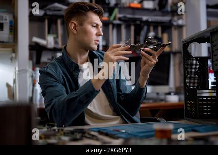 Réparateur professionnel confiant ou ingénieur restaure le PC portable en examinant les détails des pièces de l'ordinateur portable démonté. Atelier de réparation électronique, tec Banque D'Images