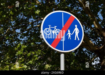 Le panneau bleu rond avec le fond d'arbre montrant que le chemin pour les cyclistes et les piétons se termine Banque D'Images