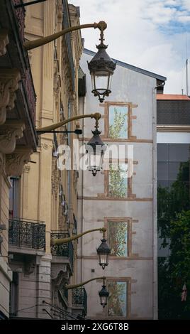Découvrez le vibrant mélange d'art et d'histoire à Lyon, où une magnifique murale rencontre un bâtiment historique magnifiquement orné avec de charmantes lanternes. Banque D'Images