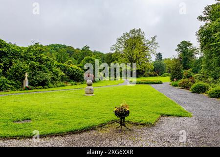 Chemins piétonniers parmi l'herbe verte dans les jardins de l'abbaye du Val-Dieu, entourés d'arbres verdoyants contre ciel gris, jour nuageux à Aubel, Belgique Banque D'Images