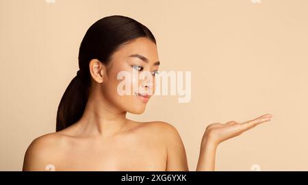 Belle femme asiatique avec de longs cheveux foncés montrant Open Palm Banque D'Images