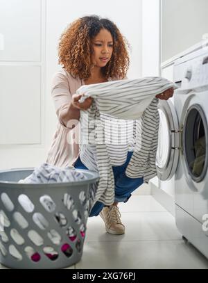 Femme, maison et incertain avec machine à laver pour la lessive dans l'entretien ménager, panier et hygiène. Femme personne, tissu et inquiet sur les corvées ou Banque D'Images