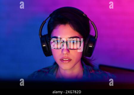 Jeune femme portant des écouteurs et des lunettes, jeu Banque D'Images