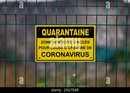 Rouge un panneau d'avertissement blanc sur une clôture indiquant en français 'quarantaine - zone interdite d'accès pour cause d'attentes de coronavirus'. , Signifiant en Engl Banque D'Images