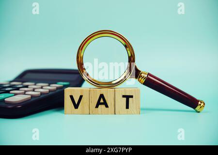 TVA avec blocs en bois lettres alphabétiques et loupe et calculatrice sur fond bleu Banque D'Images