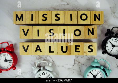 Mission Vision valeurs avec blocs en bois lettres alphabétiques et réveil sur fond de marbre Banque D'Images