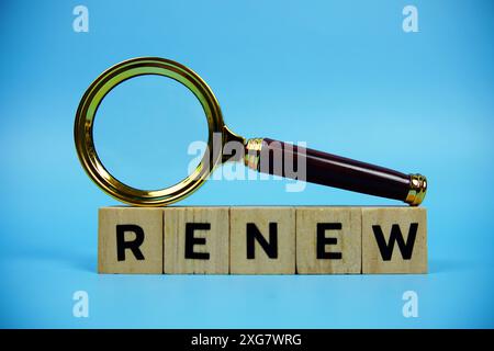 Renouveler avec des blocs en bois lettres de l'alphabet et loupe sur fond bleu Banque D'Images