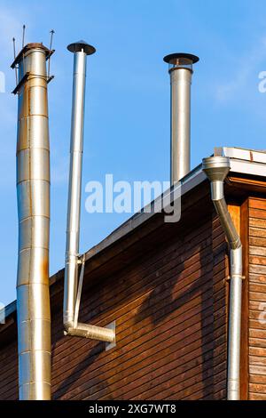 maison avec tuyaux de cheminée en acier inoxydable, photo verticale. tuyau pour évacuer la fumée de la maison. maison avec chauffage de poêle Banque D'Images