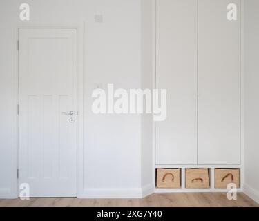Armoires de chambre modernes et contemporaines en MDF peint en blanc, avec paniers en raphia. Les placards sont conçus par l'architecte dans un style minimaliste et simple. Banque D'Images