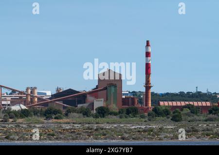 Complexe industriel avec cheminée rayée rouge-blanc, entouré de verdure et d'un étang, pour-sur-mer, Bouches-du-Rhône, sud de la France, journée ensoleillée Banque D'Images