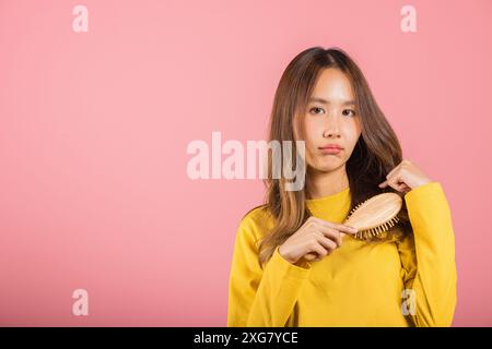 Jeune belle femme asiatique bouleversée avec un peigne et des cheveux à problème, Portrait femme choquée souffrance Banque D'Images