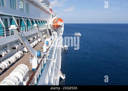 La vue matinale d'un grand bateau de croisière et de petits bateaux tendres emmenant les touristes à l'île de Grand Cayman. Banque D'Images