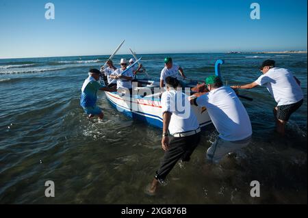 Malaga, Espagne. 07 juillet 2024. On voit des hommes pousser un « jabega » (bateau de pêche) vers la mer à la plage alors qu'ils participent à l'exposition « la Tirada del Copo » sur la plage de Los Boliches. Chaque année à Fuengirola, les habitants célèbrent une vieille tradition de pêche connue sous le nom de « la Tirada del Copo » pour mettre en valeur les compétences et le métier des marins et des pêcheurs lors de la capture de poissons dans la mer. Comme le veut la tradition, pendant la « Tirada del Copo », les marins jettent des filets dans la mer, formant un demi-cercle, tandis que d'autres tirent les filets vers la plage pour capturer tous les poissons. Banque D'Images