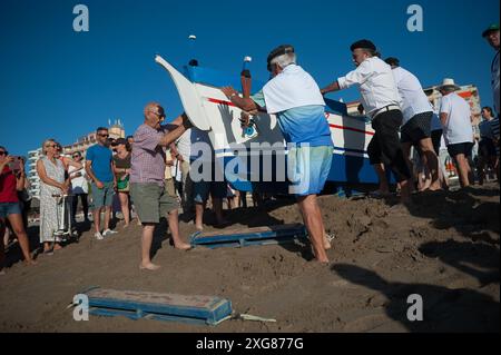 Malaga, Espagne. 07 juillet 2024. On voit des hommes pousser un « jabega » (bateau de pêche) vers la mer à la plage alors qu'ils participent à l'exposition « la Tirada del Copo » sur la plage de Los Boliches. Chaque année à Fuengirola, les habitants célèbrent une vieille tradition de pêche connue sous le nom de « la Tirada del Copo » pour mettre en valeur les compétences et le métier des marins et des pêcheurs lors de la capture de poissons dans la mer. Comme le veut la tradition, pendant la « Tirada del Copo », les marins jettent des filets dans la mer, formant un demi-cercle, tandis que d'autres tirent les filets vers la plage pour capturer tous les poissons. Banque D'Images