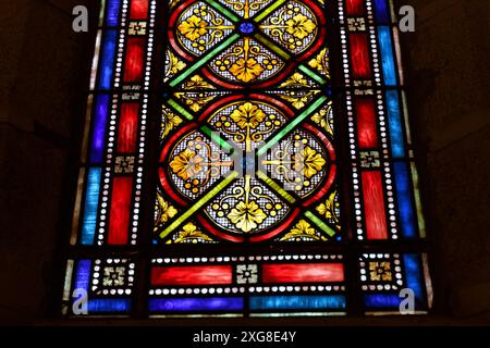 Une vue rapprochée d'un vitrail vibrant dans une église, présentant des images religieuses complexes et des motifs colorés. Banque D'Images