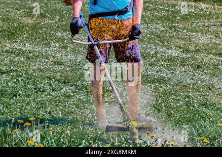 Le gardien de sol ne protégeait pas la peau des jambes lorsqu'il travaillait avec des tibias mangeurs de mauvaises herbes qui étaient couverts de particules d'herbe déchiquetées. Banque D'Images