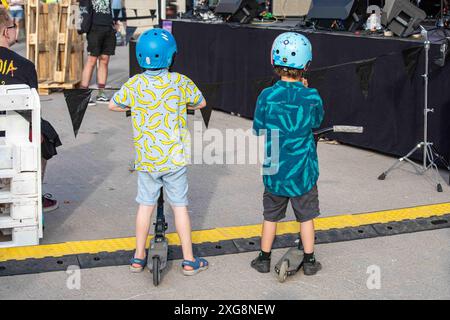 Les enfants avec des scooters et des casques jouissant d'un concert gratuit au Tapiolan Kulttuuriaukio à Espoo, Finlande Banque D'Images