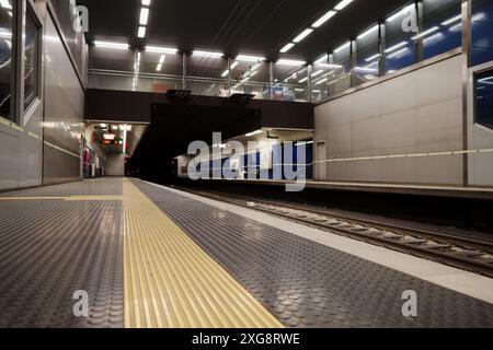 Mise au point sélective et vue à angle réduit sur la plate-forme du métro souterrain avec des éléments de design élégants, avec éclairage par le haut lumineux, couleur bleue et grise Banque D'Images