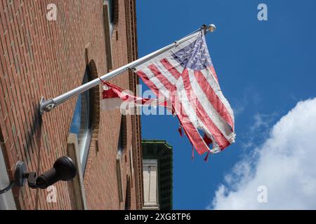 Un drapeau américain en lambeaux volant devant le bureau de poste américain à Flint Michigan USA Banque D'Images